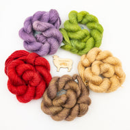 A group of Colinton Australia Lace yarn in colors red, green, purple, tan, and brown