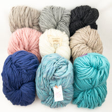 Load image into Gallery viewer, A collection of giant skeins of wool yarn in various solid and melange colors, including beige, black, blue, pink, white, and turquoise.
