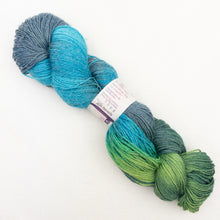 Load image into Gallery viewer, A blue and green variegated skein of Lornas Laces Solemate sock yarn on a white background.
