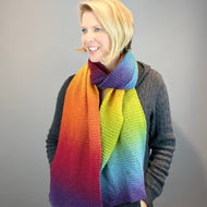 Woman wearing a rainbow garter stitch scarf knit in Kauni Effektgarn color EQ
